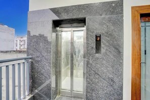 An elevator with a digital display showing the number 2, adjacent to a door with a wooden frame. - FabHotel Royal Inn (Noida)