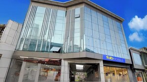 Een modern hotelgebouw met een glazen gevel, een duidelijke ingang en een bordje met 'fab hotels'.