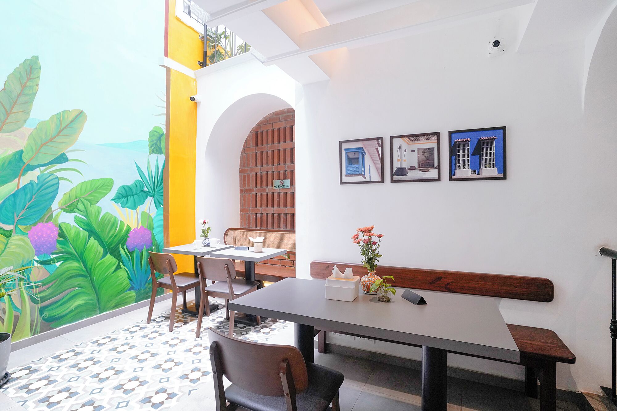 A dining area with a table, chairs, and a bench. There are framed pictures on the wall.