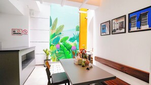 Un interior moderno con una zona de comedor, un cuadro de hojas tropicales y un cartel de 'No Fumar'.