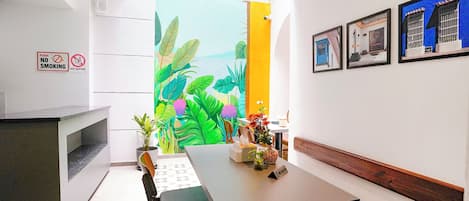 A modern interior with a dining area, a painting of tropical leaves, and a 'No Smoking' sign.