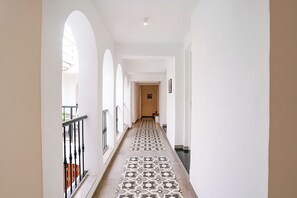 A long hallway with patterned flooring, white walls, and a staircase on the left. - FabHotel Casa Bharat (Panaji)