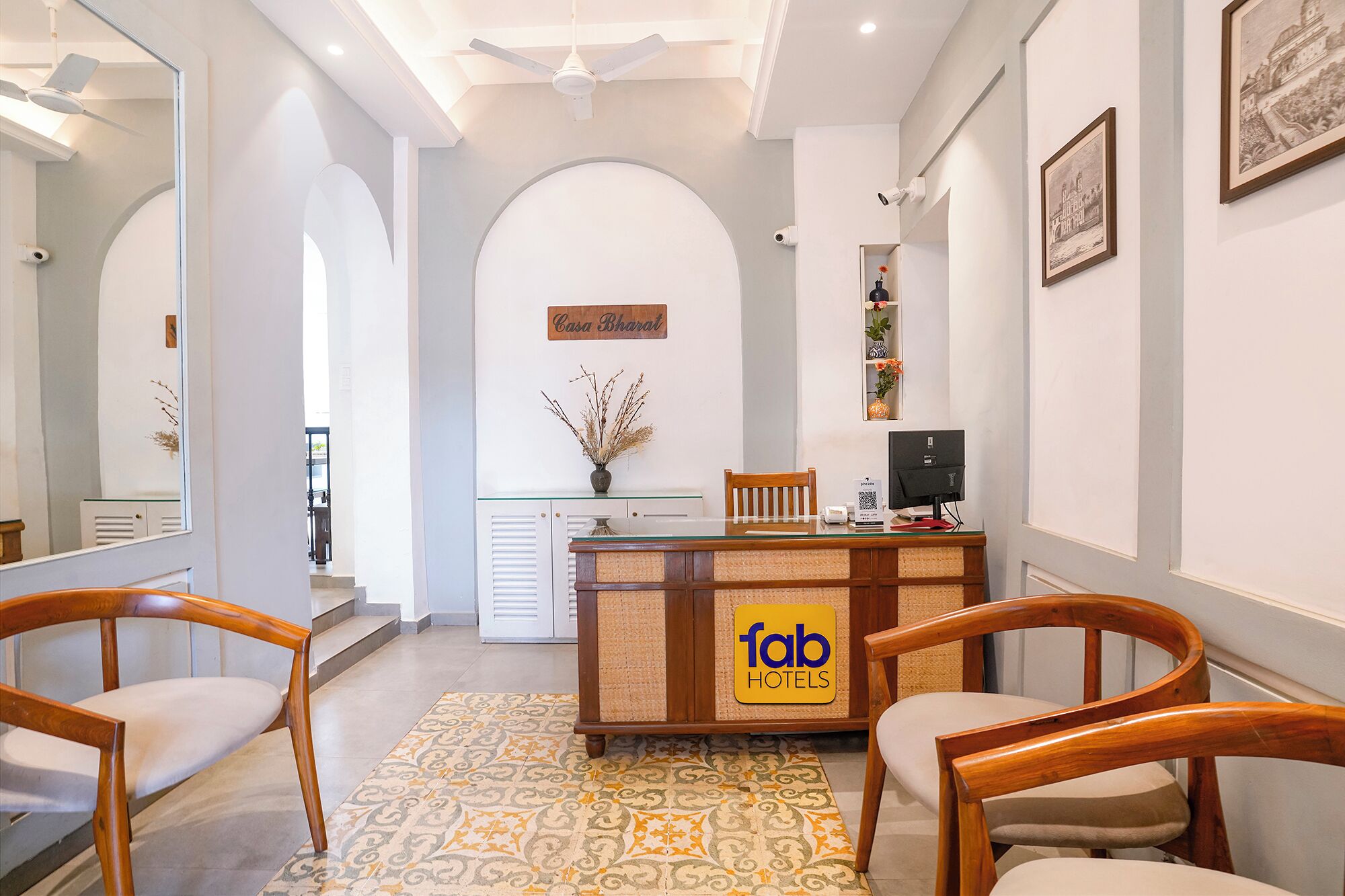 Zona de recepción de hotel con mostrador, sillas, un jarrón decorativo y un letrero de Fab Hotels.