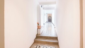 Un pasillo con suelo estampado que conduce a una puerta con candelabro.