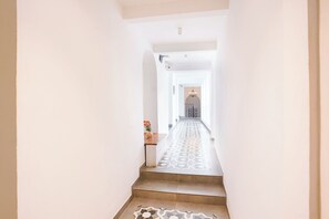 A hallway with a patterned floor leading to a door with a chandelier.