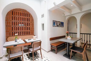 A restaurant interior with brick walls, white tables, and benches.