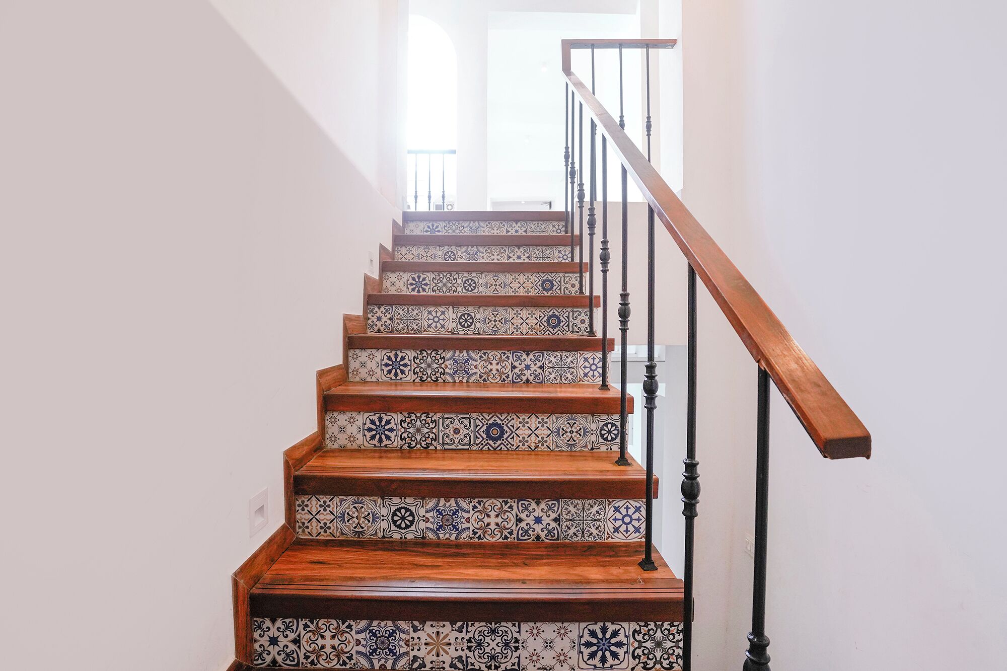 Una escalera con barandilla de madera y pasamanos, que conduce a un piso superior.