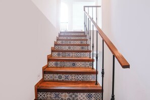 A staircase with a wooden handrail and a railing, leading to an upper floor.