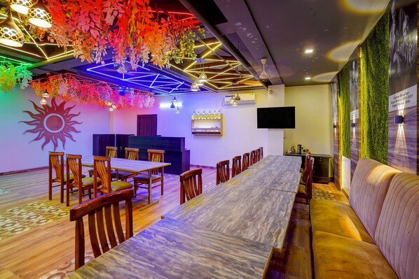 A dining area with a long table, chairs, and a sofa. - FabHotel SV Grand I - 1 KM From Kashi Vishwanath Temple (Varanasi)
