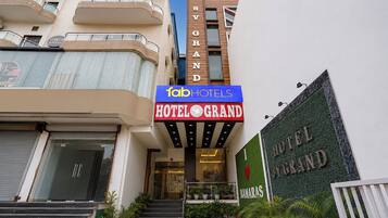 L’entrée d’un hôtel, avec une enseigne indiquant « Hôtel Grand » et « Tab Hotels » au-dessus.