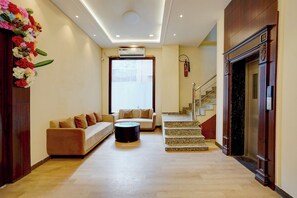 Um hall de hotel com um sofá, uma mesa de centro, uma escada e uma lareira.