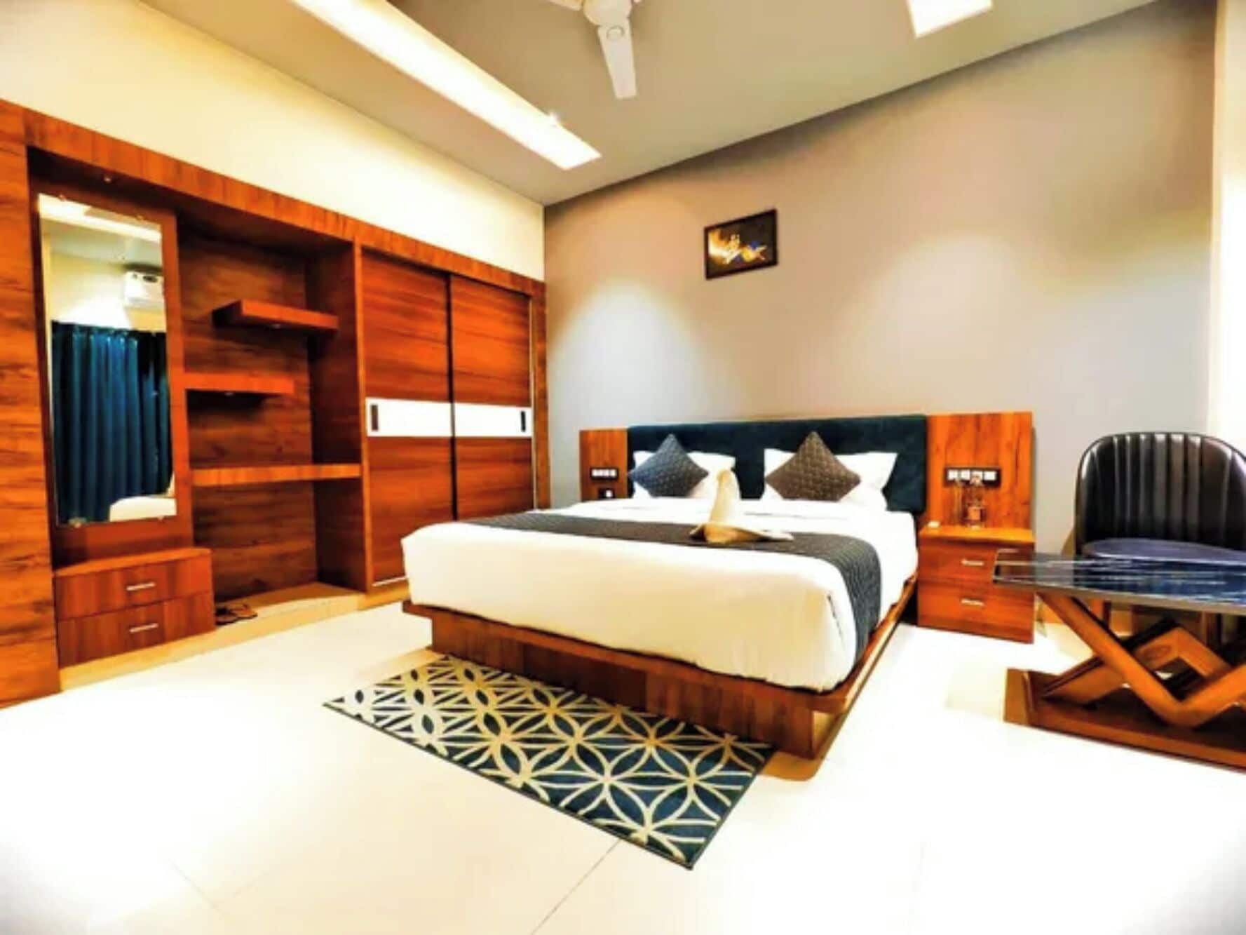 A hotel room with a large bed, a desk, a wardrobe, and a mirror.