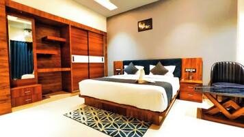 A hotel room with a large bed, a desk, a wardrobe, and a mirror.