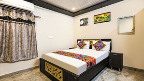 A hotel room with a bed, a nightstand, a wall clock, a painting, and a mirror. - Fabhotel Ssd Grand (Visakhapatnam)