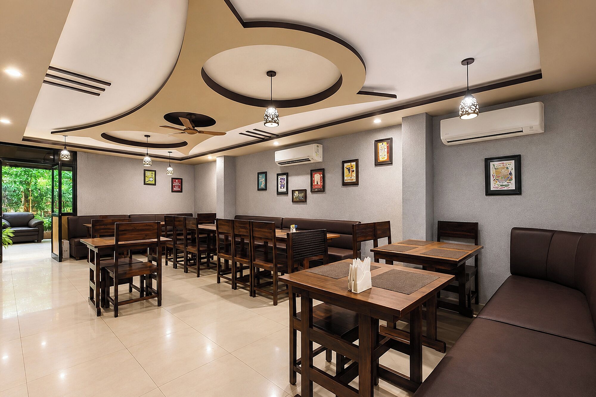 A restaurant with a modern interior, featuring wooden tables and booths, ceiling fans, and wall-mounted air conditioning units.