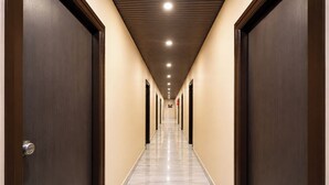 A hotel hallway with doors on both sides, a tiled floor, and recessed lighting on the ceiling. - Fabhotel Ssd Grand (Visakhapatnam)