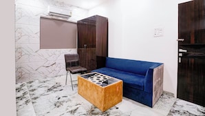 A room with a marble-patterned floor, a blue sofa, a wooden side table, and dark wooden wardrobes. - Fabhotel Yash Residency Ii (Ambernath)