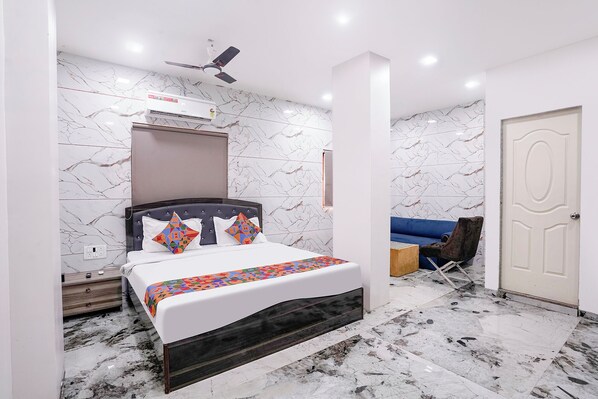 A bedroom with a bed, a ceiling fan, an air conditioning unit, and a door.