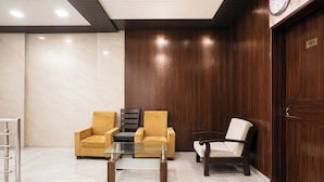 A lobby with two armchairs, a glass coffee table, and a wooden door with a number plaque. - Fabhotel Yash Residency Ii (Ambernath)