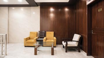 A lobby with two armchairs, a glass coffee table, and a wooden door with a number plaque.