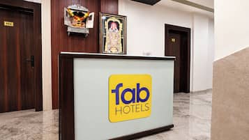 A hotel reception desk with a 'fab hotels' sign, a clock, and a small shrine with offerings.