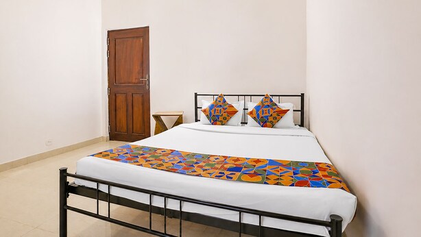 A single bed with a metal frame, a wooden door, and a small bedside table. - Fabhotel Bounty Yatra (Arpora)