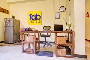 A hotel reception desk with a sign reading 'fab HOTELS', a refrigerator, a computer, and office chairs. - FabHotel Bounty Yatra (Arpora)
