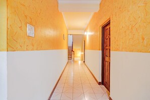 A hallway with patterned walls, a wooden door, and a staircase leading to another level. - FabHotel Bounty Yatra (Arpora)