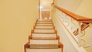 A staircase with a wooden handrail and a white balustrade. - Fabhotel Bounty Yatra (Arpora)