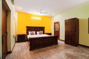 A bedroom with a wooden bed, a wardrobe, and a ceiling fan. - Fabhotel Zamindar Garden (Puducherry)