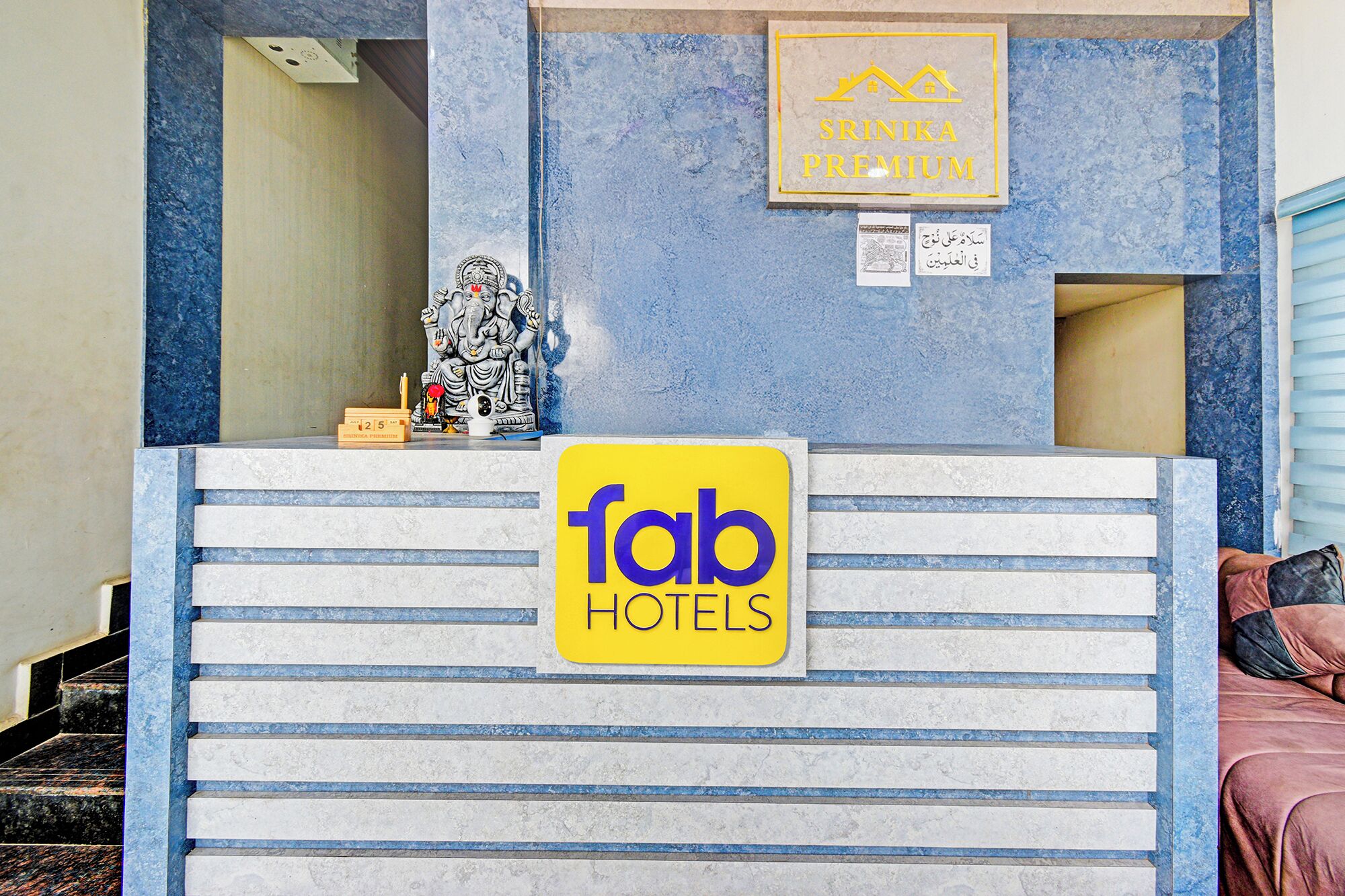 Una reception hotel con un cartello per 'fab hotels' e una statua di una divinità.
