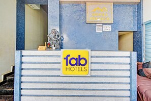 Una recepción de hotel con un cartel de 'fab hotels' y una estatua de una deidad.