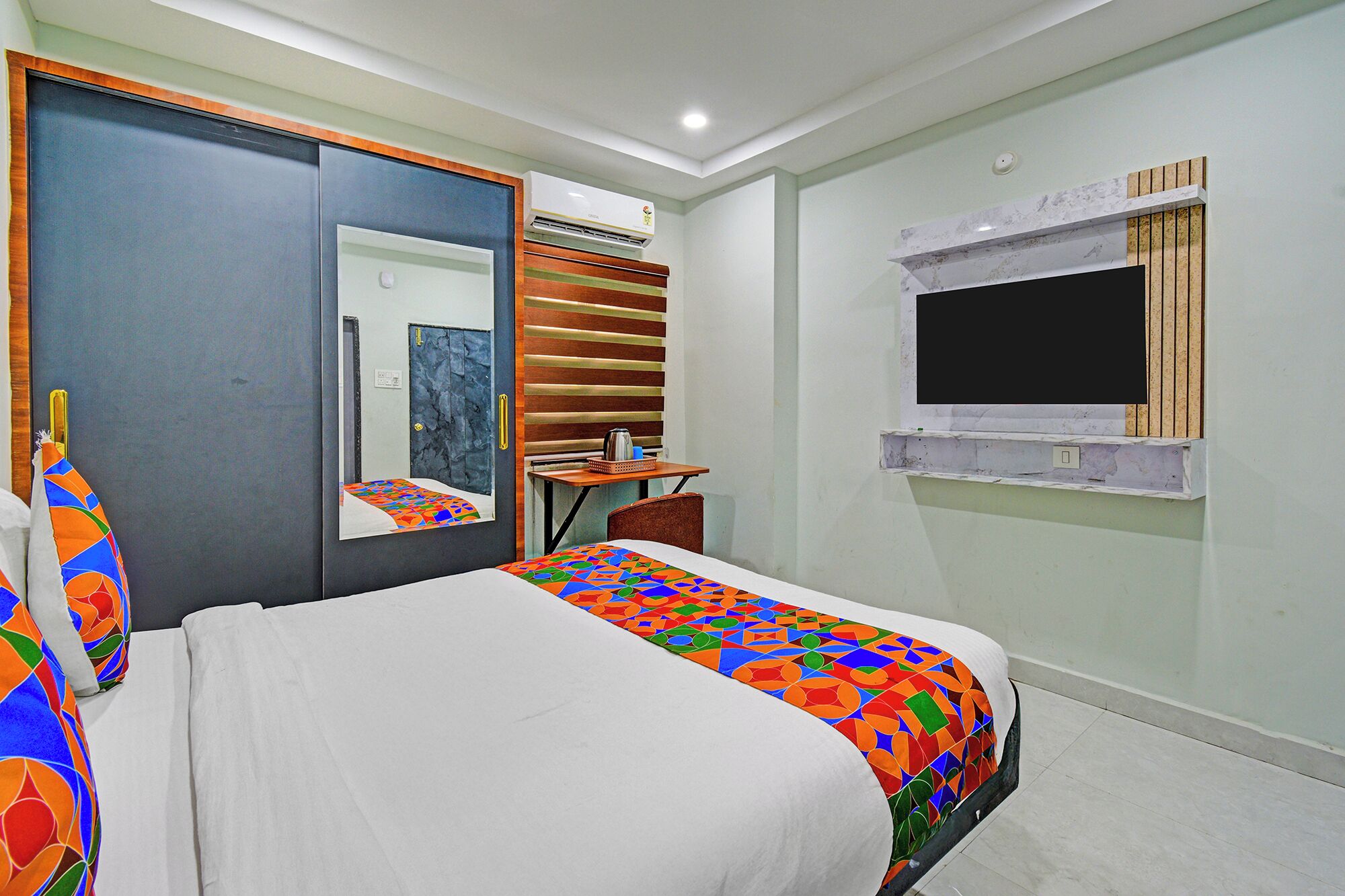 Habitación de hotel con cama, escritorio, silla, espejo y ventana.