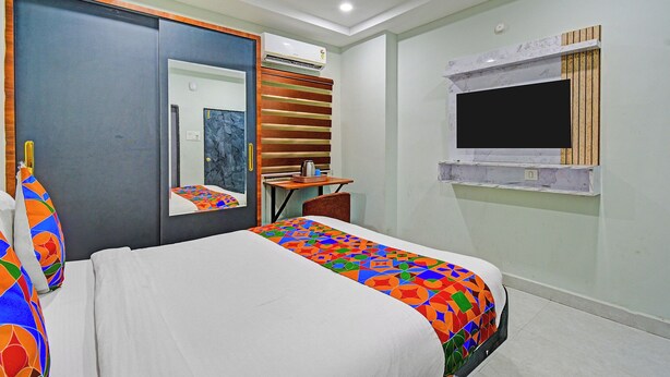 Een hotelkamer met een bed, een bureau, een stoel, een spiegel en een raam.