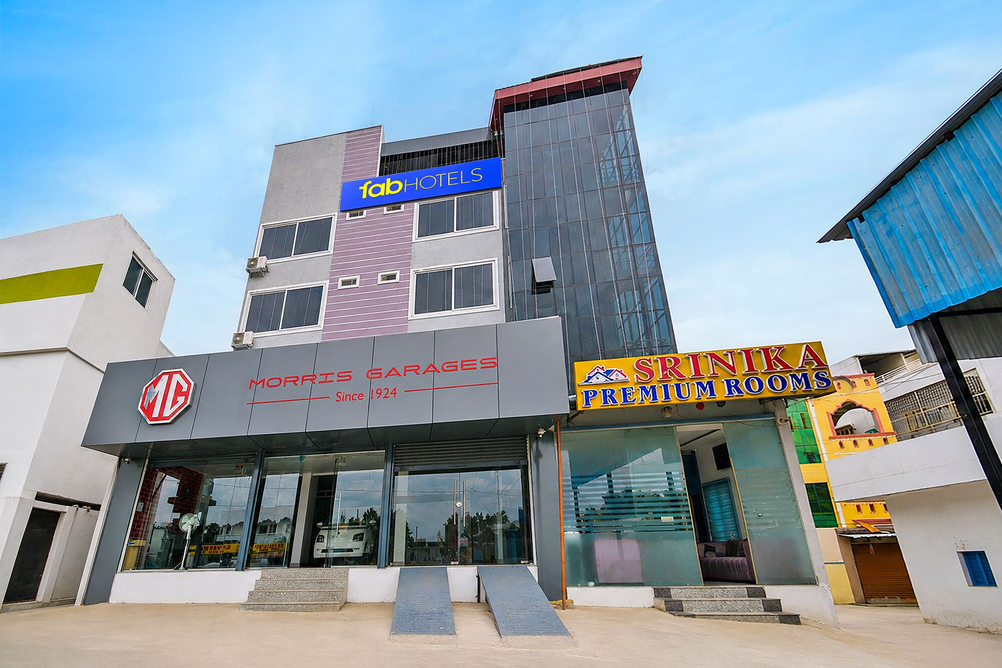 Een gebouw met een bord voor Morris Garages en een bord voor Sritika Premium Rooms.