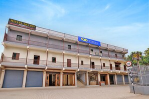 A multi-story hotel with balconies, a speed limit sign, and closed shop fronts. - FabHotel Sky Inn I (Ahmedabad)