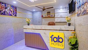 Ein Hotelrezeptionstresen mit Marmorplatte, Deckenventilator und einem Schild mit der Aufschrift 'fab hotels'.