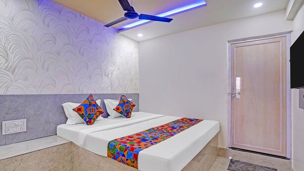 Ein modernes Schlafzimmer mit einem Bett, einem Deckenventilator, einer Wand mit Struktur und einer Tür.