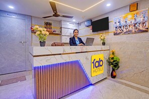 A hotel reception desk with a modern design, a flat-screen TV, and a sign indicating the hotel's name. - FabHotel Sky Inn I (Ahmedabad)