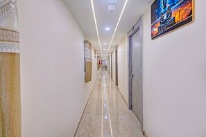 A hotel corridor with a polished marble floor, a security camera, and a framed artwork on the wall. - Fabhotel Sky Inn I (Ahmedabad)