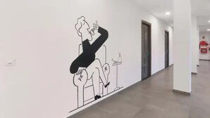 A hallway with a wall mural of a seated figure, doors, and a fire extinguisher. - Fabhotel Bsa (Lucknow)