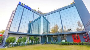 A modern hotel with a glass facade, a prominent blue sign, and a red door. - Fabhotel Bsa (Lucknow)