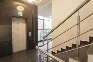 Un interior modern amb una escala, una porta amb un rètol i una finestra.