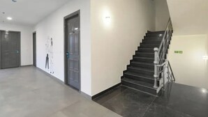 A modern interior with a staircase, a door, and a wall-mounted light fixture. - Fabhotel Bsa (Lucknow)