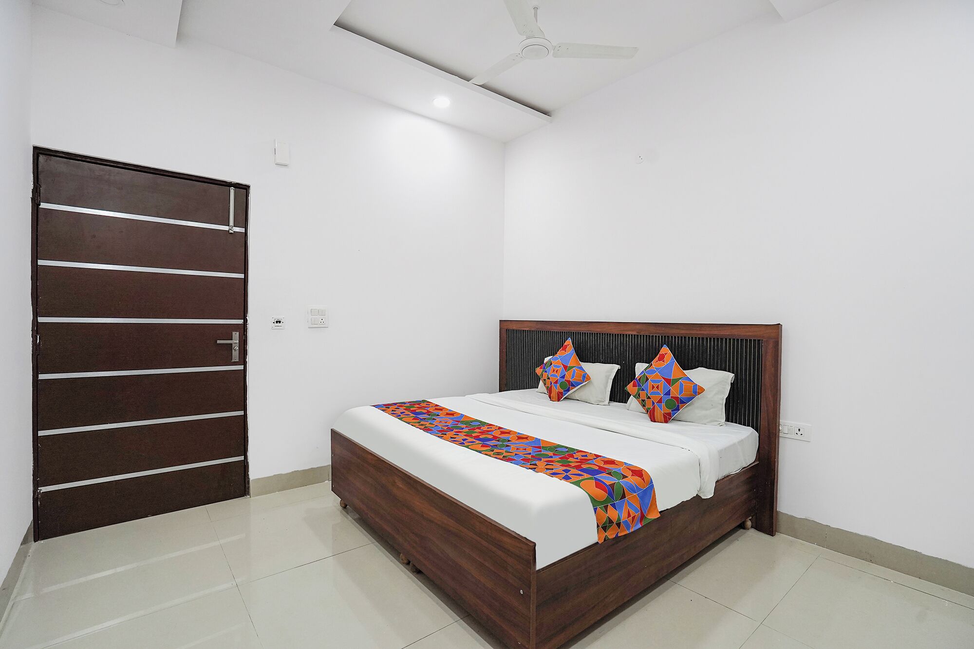 Un dormitorio con cama, una puerta de madera y un ventilador de techo.