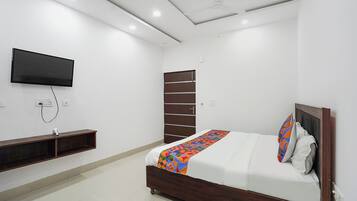 A bedroom with a bed, a TV mounted on the wall, and a door.