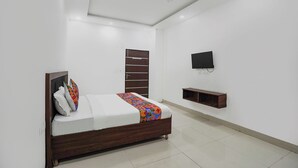 Un dormitorio con cama, televisor, ventilador de techo y armario de madera.
