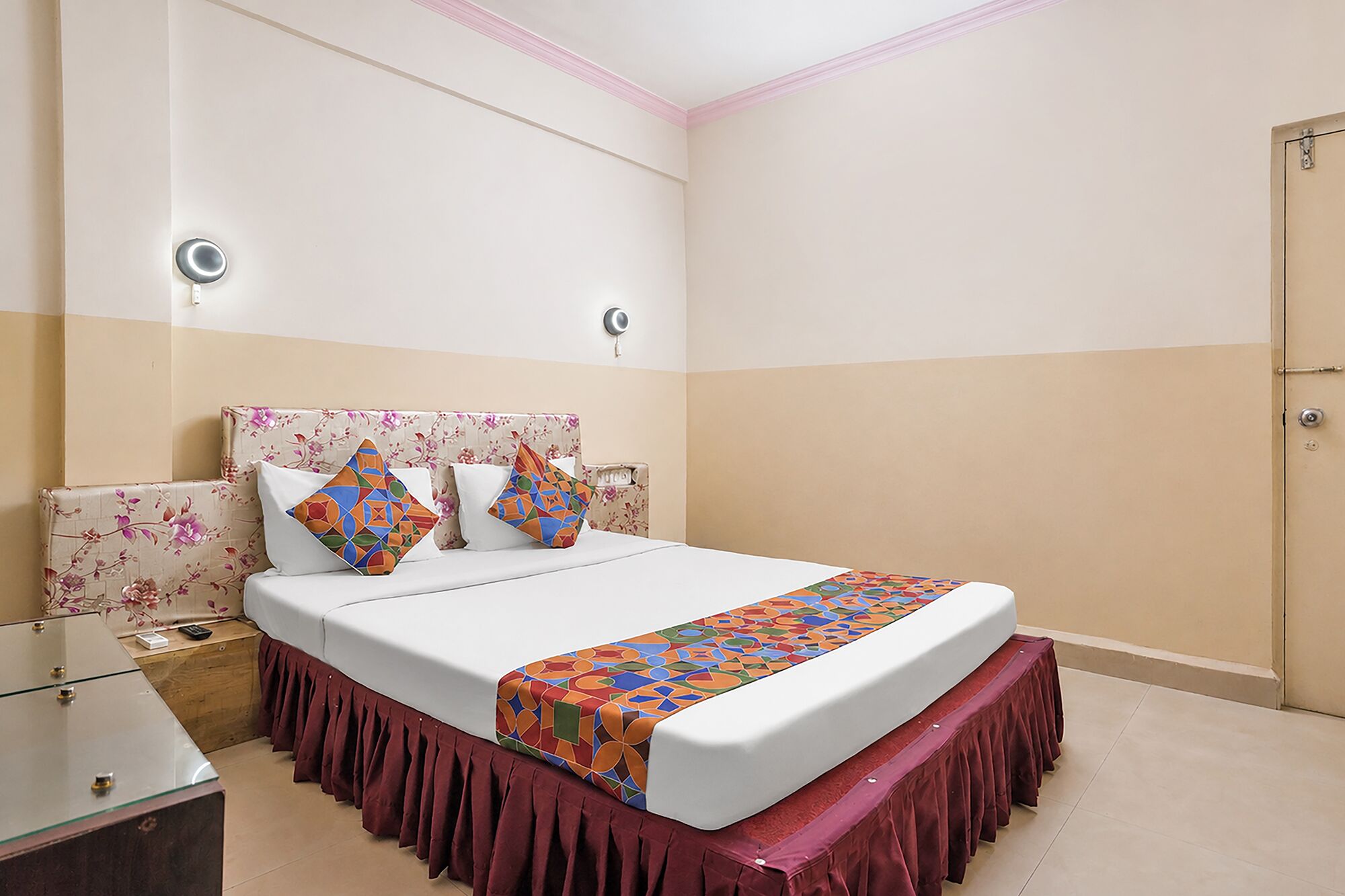 A hotel room with a bed, bedside tables, a wardrobe, and a mirror.