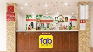 A hotel reception area with a wooden reception desk, a 'fab hotels' sign, and a wall with a 'no smoking' sign and a distance chart.