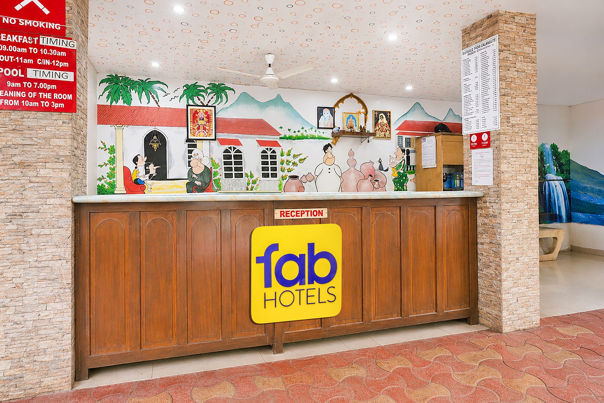 Una recepción con un cartel de Fab Hotels, un letrero de no fumar y una pared con un mural.